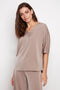 Model wearing UP! Belize Satin V-Neck Short Sleeve Top in Almond, front view.