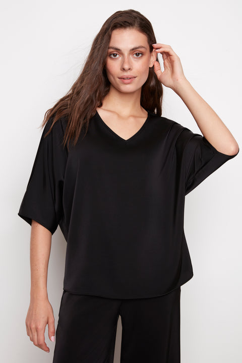 Model wearing UP! Belize Satin V-Neck Short Sleeve Top in Black, front view.