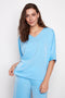 Model wearing UP! Belize Satin V-Neck Short Sleeve Top in Celeste Blue, front view.