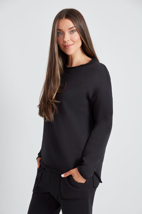 Woman wearing the French Terry Raw Edge Top in Black, side view.
