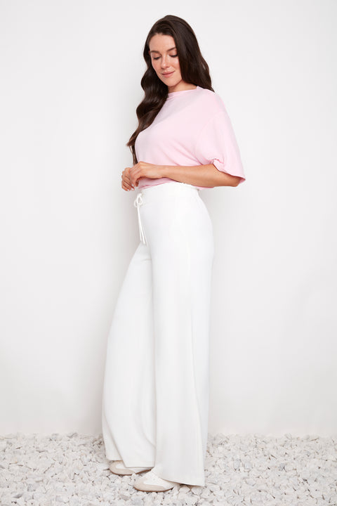 Side view of model wearing UP! Vegan Silk Wide-Leg Full-Length Pant in White with tie-front ruched waist detail.