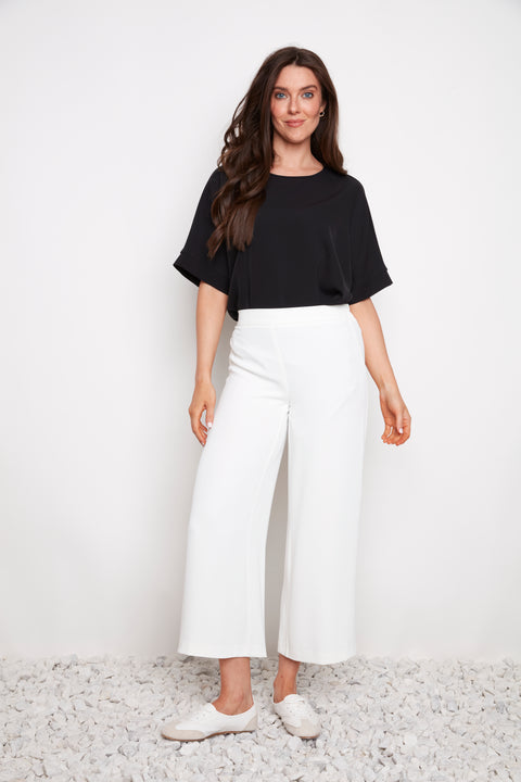 Model wearing UP! Vegan Silk Wide Leg Cropped Pant in Cream, front view.
