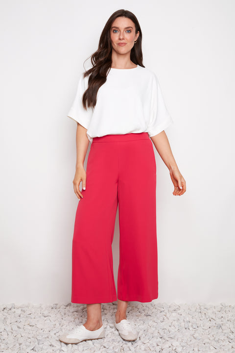Model wearing UP! Vegan Silk Wide Leg Cropped Pant in Dahlia Red, front view.