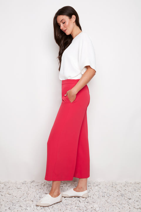 Model wearing UP! Vegan Silk Wide Leg Cropped Pant in Dahlia Red, side view.
