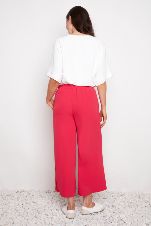 Model wearing UP! Vegan Silk Wide Leg Cropped Pant in Dahlia Red, back view.