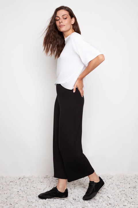 Side view of model wearing UP! Provence Wide Leg Pintuck Crop Pant in Black with exposed pintuck seam detail.