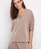 Model wearing UP! Belize Satin V-Neck Short Sleeve Top in Almond, front view.