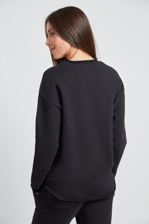 Woman wearing the French Terry Raw Edge Top in Black, back view.