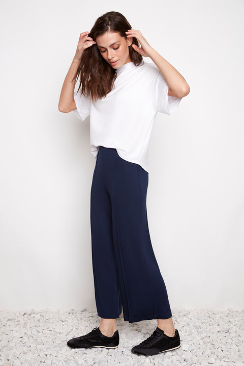 Side view of model wearing UP! Provence Wide Leg Pintuck Crop Pant in Harbor Navy with exposed pintuck seam detail.